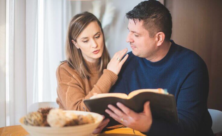 Married couple reading bible together at home. By tutye/stock.adobe.com